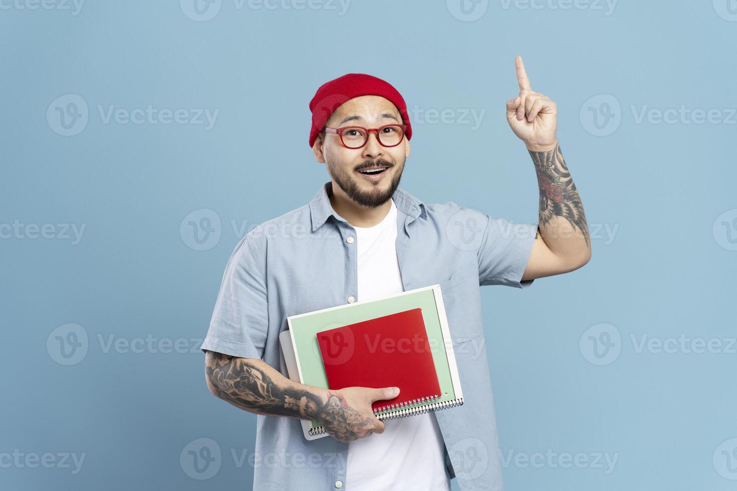 Asian man having an idea is holding notebooks and pointing upwards photo