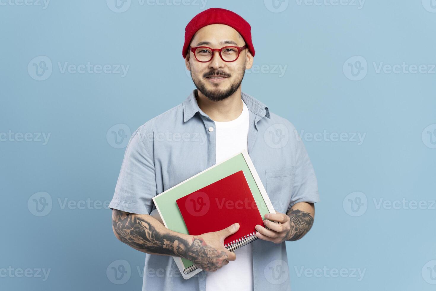 Asian male student holding notebooks on blue background photo