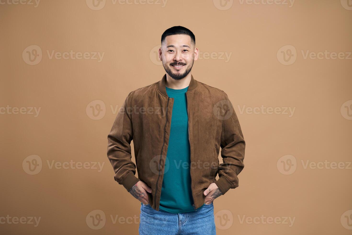 Young man smiling with hands in pockets is feeling confident photo