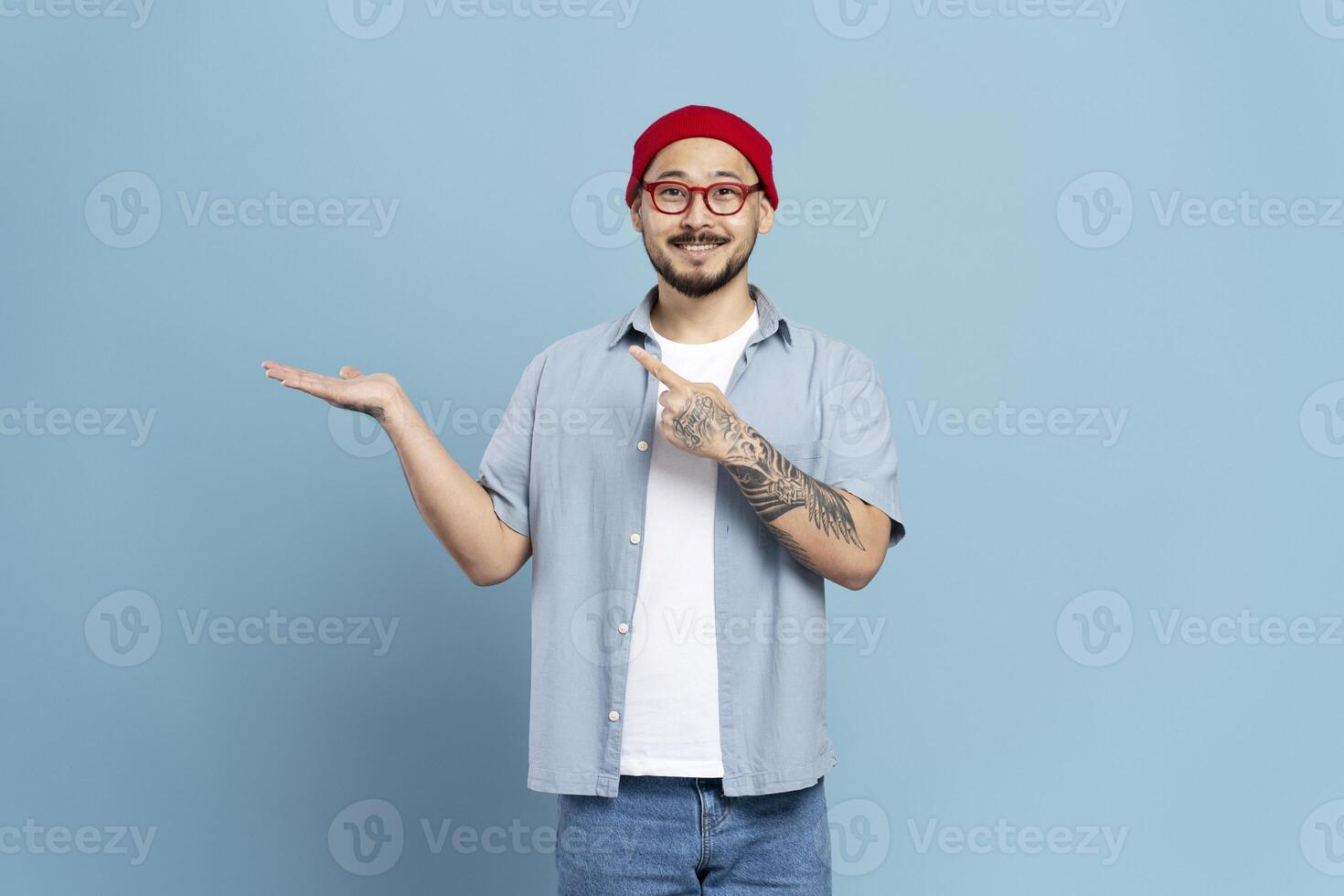 Smiling man pointing at empty hand presenting something on blue background photo