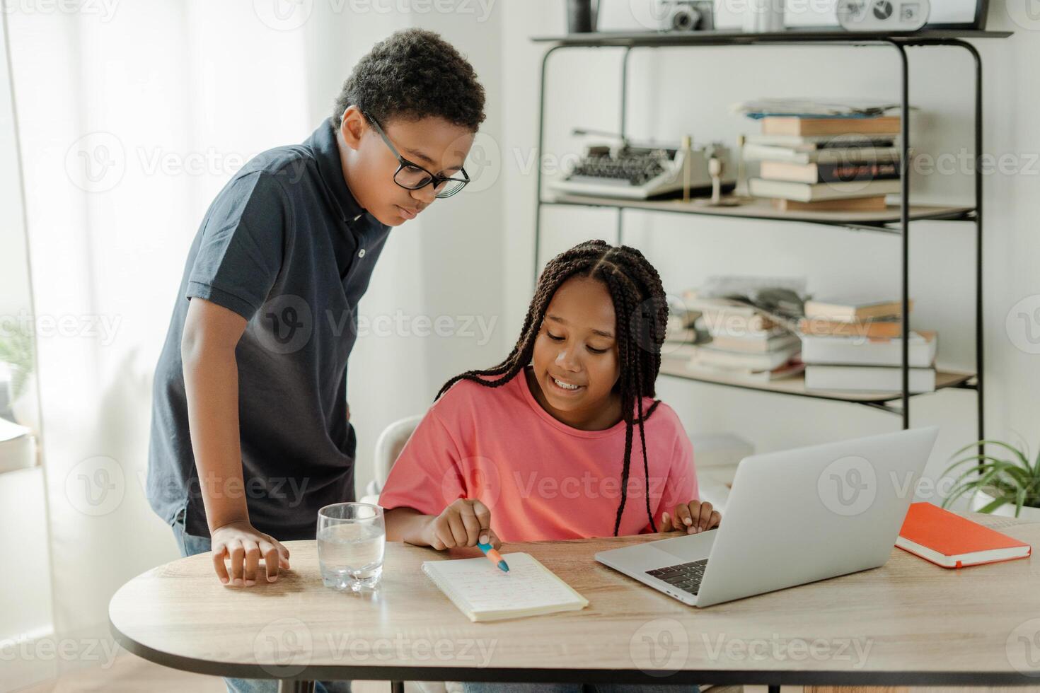 Two students collaborating on school project at home using laptop photo