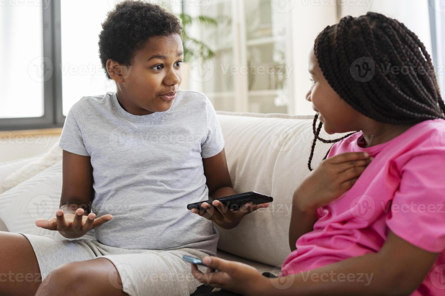Two kids having fun using technology on the couch at home photo