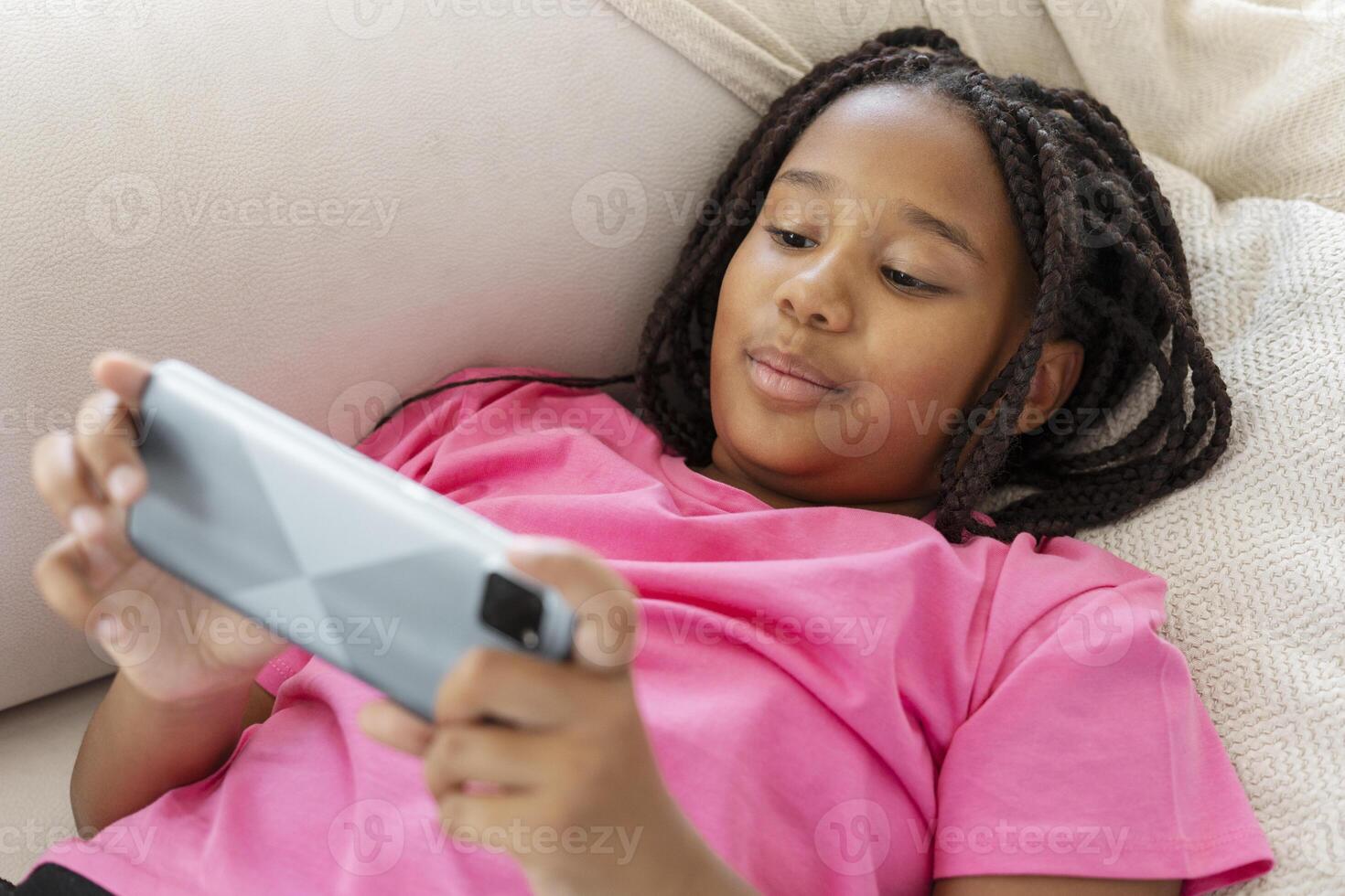 Young girl lying on couch using smartphone at home photo