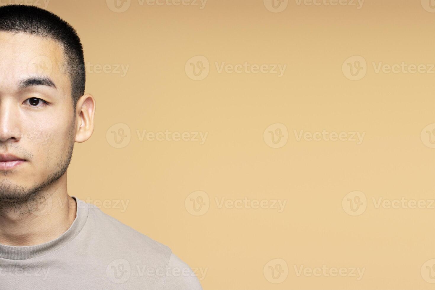 Serious young asian man looking at camera on yellow background with copy space photo