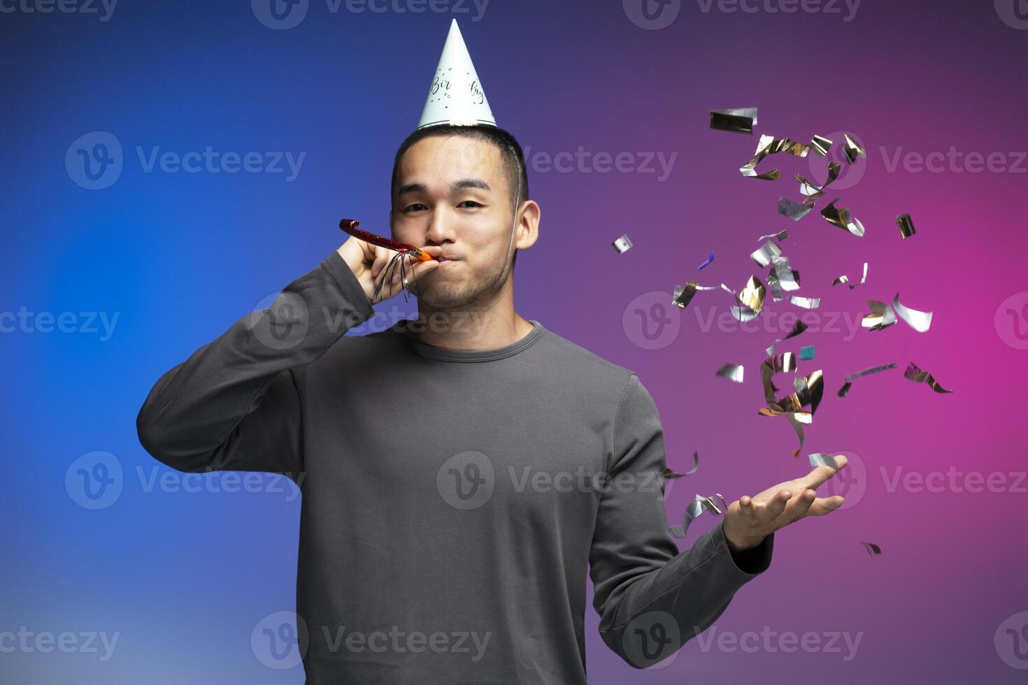 Young man celebrating with party blower and confetti photo