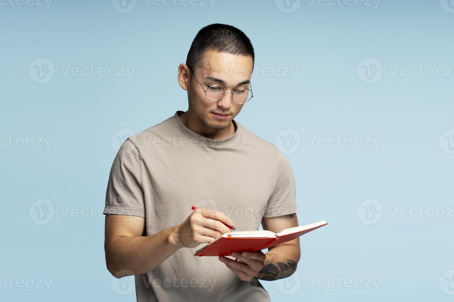 Young man taking notes and reading a book on blue background photo