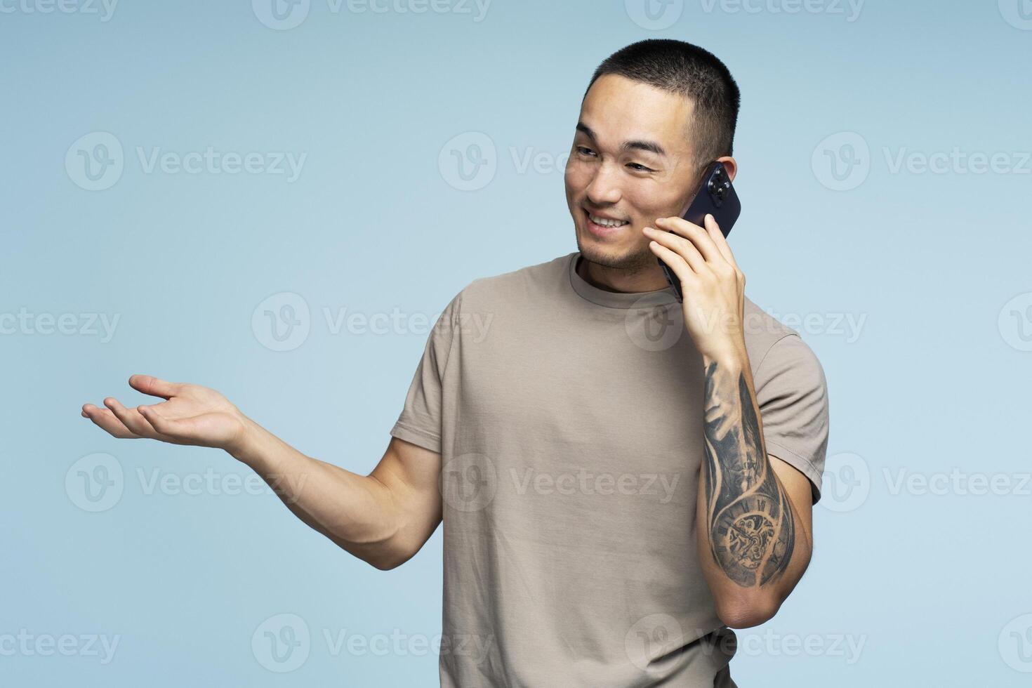 Young man gesturing while having phone conversation on blue background photo