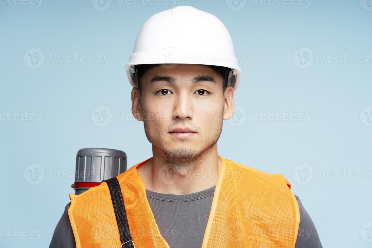 Young asian architect wearing safety vest and hard hat posing on blue background photo