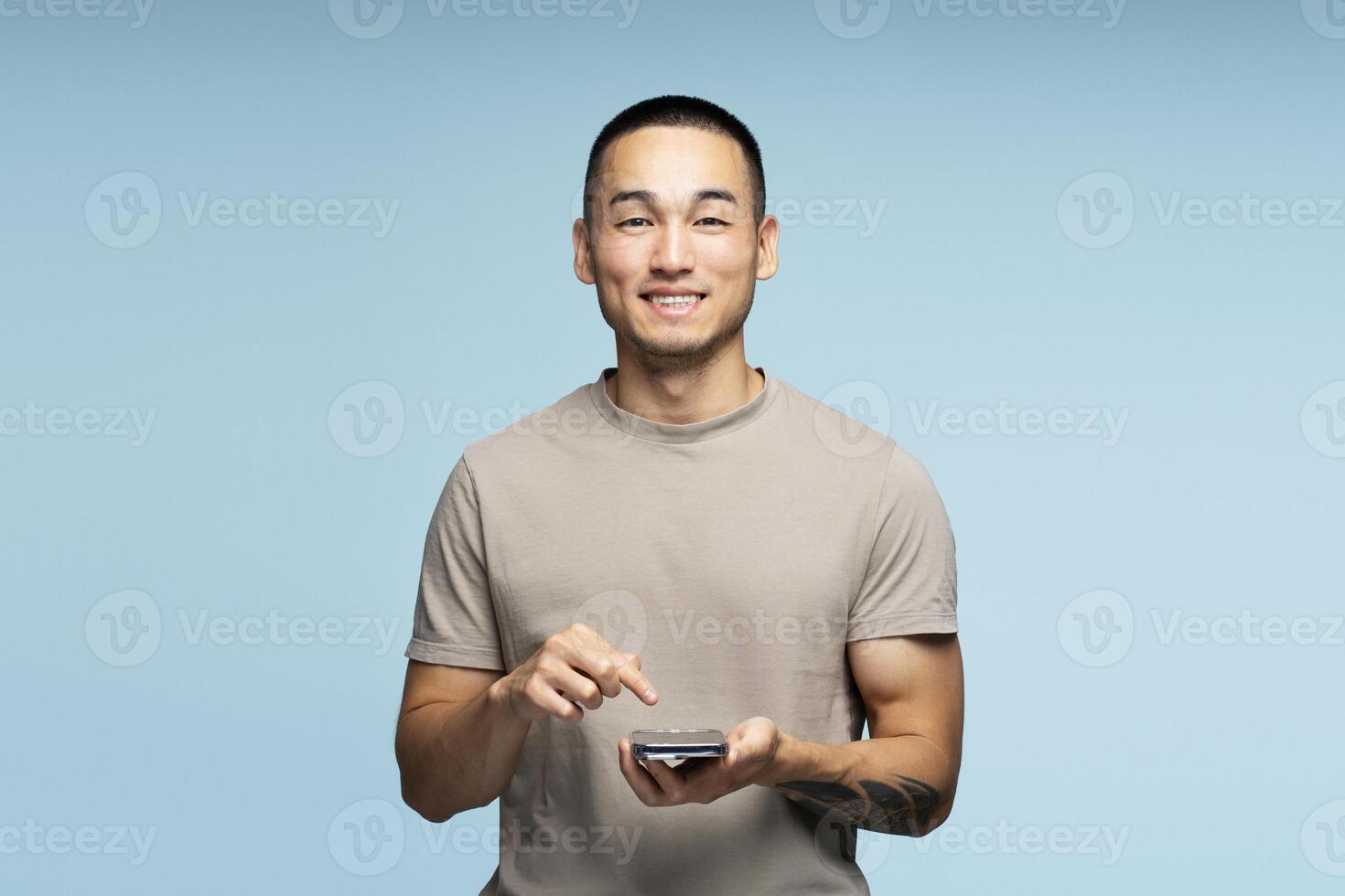 Smiling young man using smartphone app on blue background photo