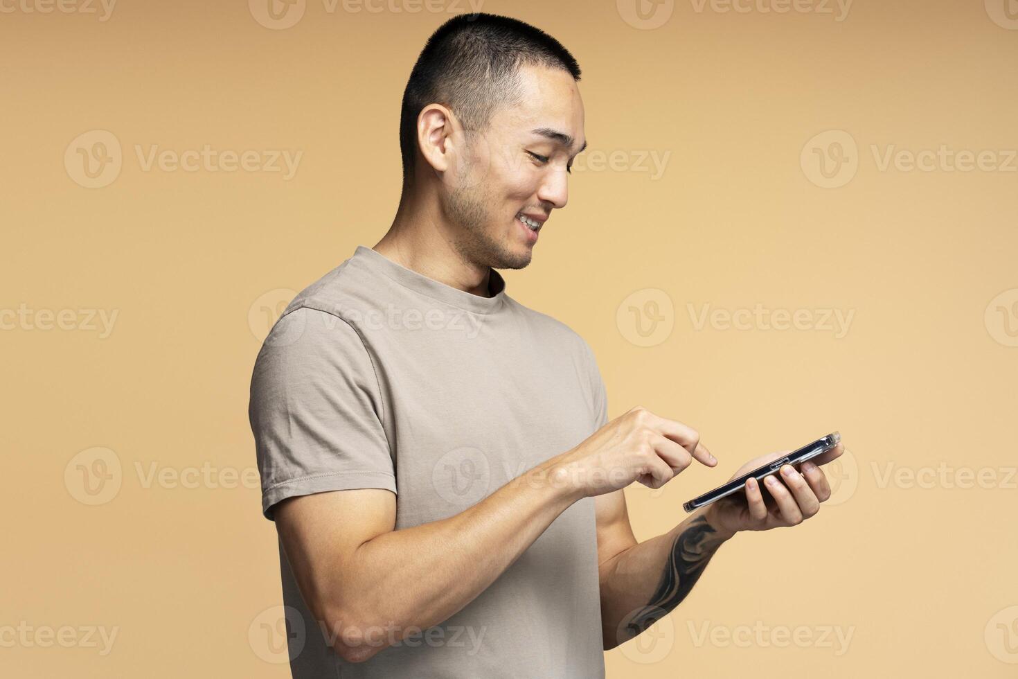 Happy man using smartphone on beige background photo