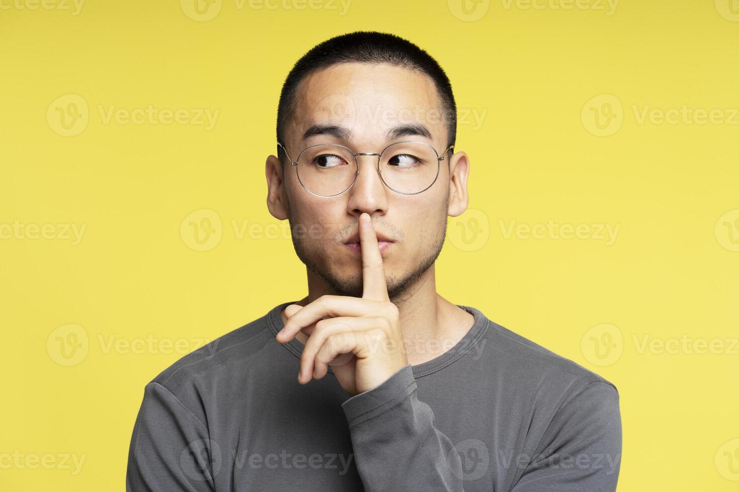 Young man making silence gesture with finger on lips photo