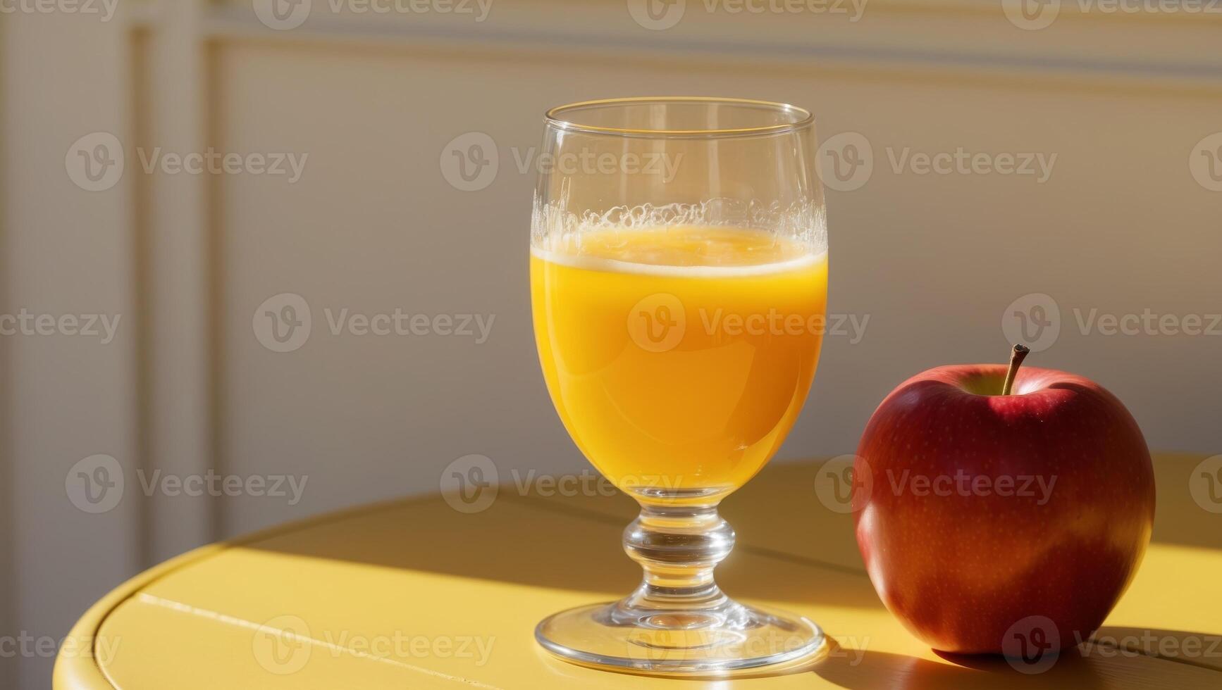 A glass of orange juice and an apple on a table photo