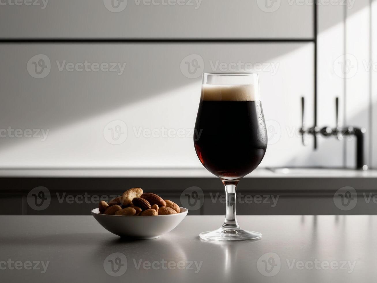 A glass of beer and a bowl of nuts on a counter photo