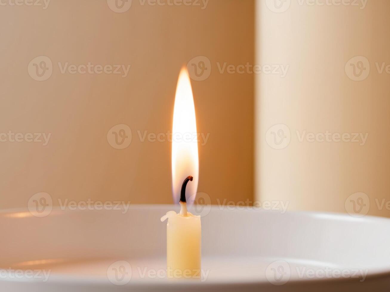 A single candle is lit in a white bowl photo