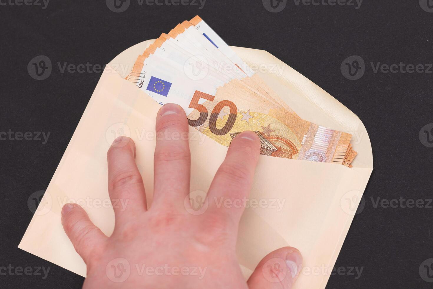 Hand Holds An Orange Paper Envelope with Stack of 50-Euro Banknotes Inside. Salary in Cash. Tax-Free System. Euro Currency. Payments with No Taxes. Orange Paper Money. A Lot of Fifty-Euro Bills photo