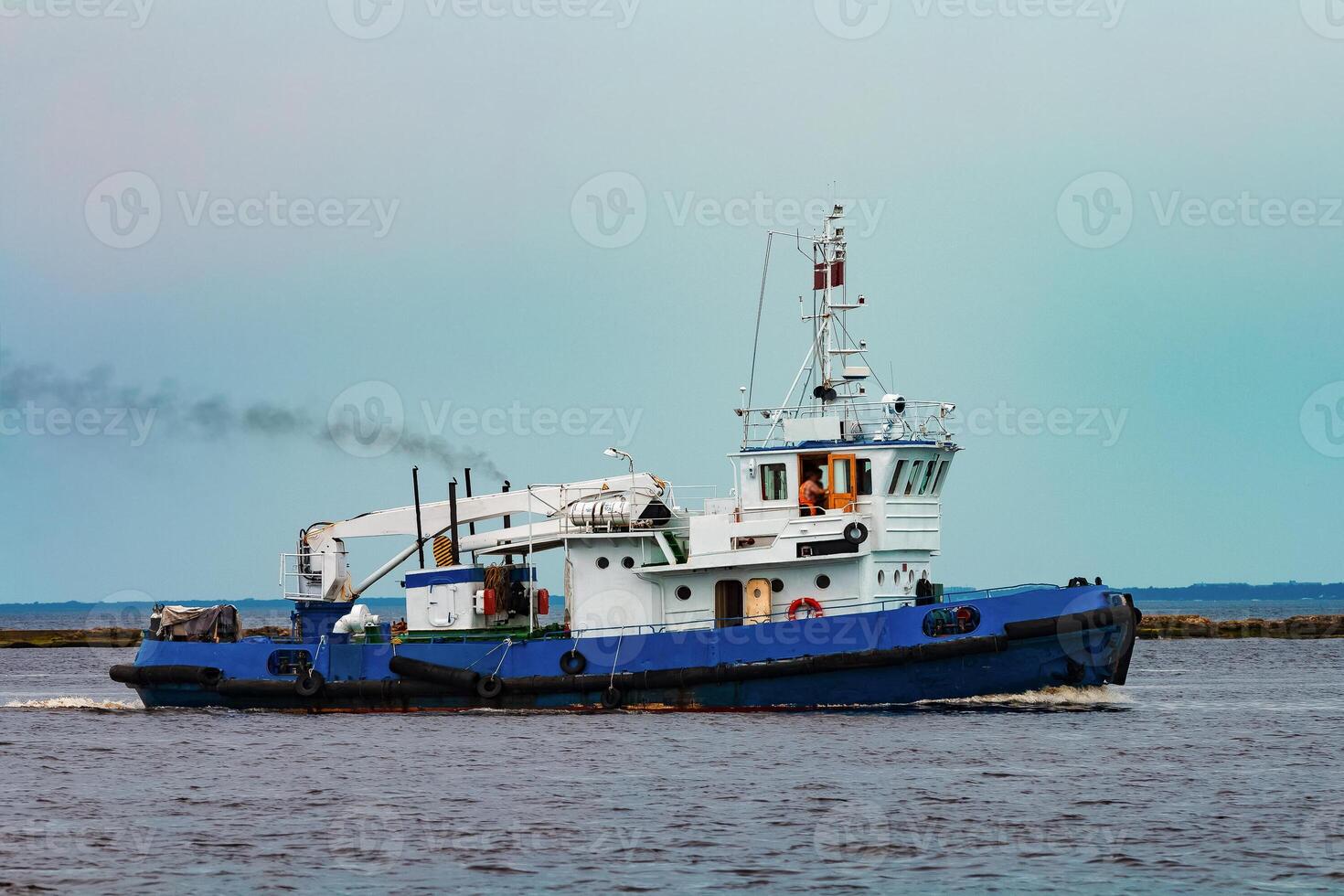 Blue tug ship moving to the cargo terminal. Industrial services photo