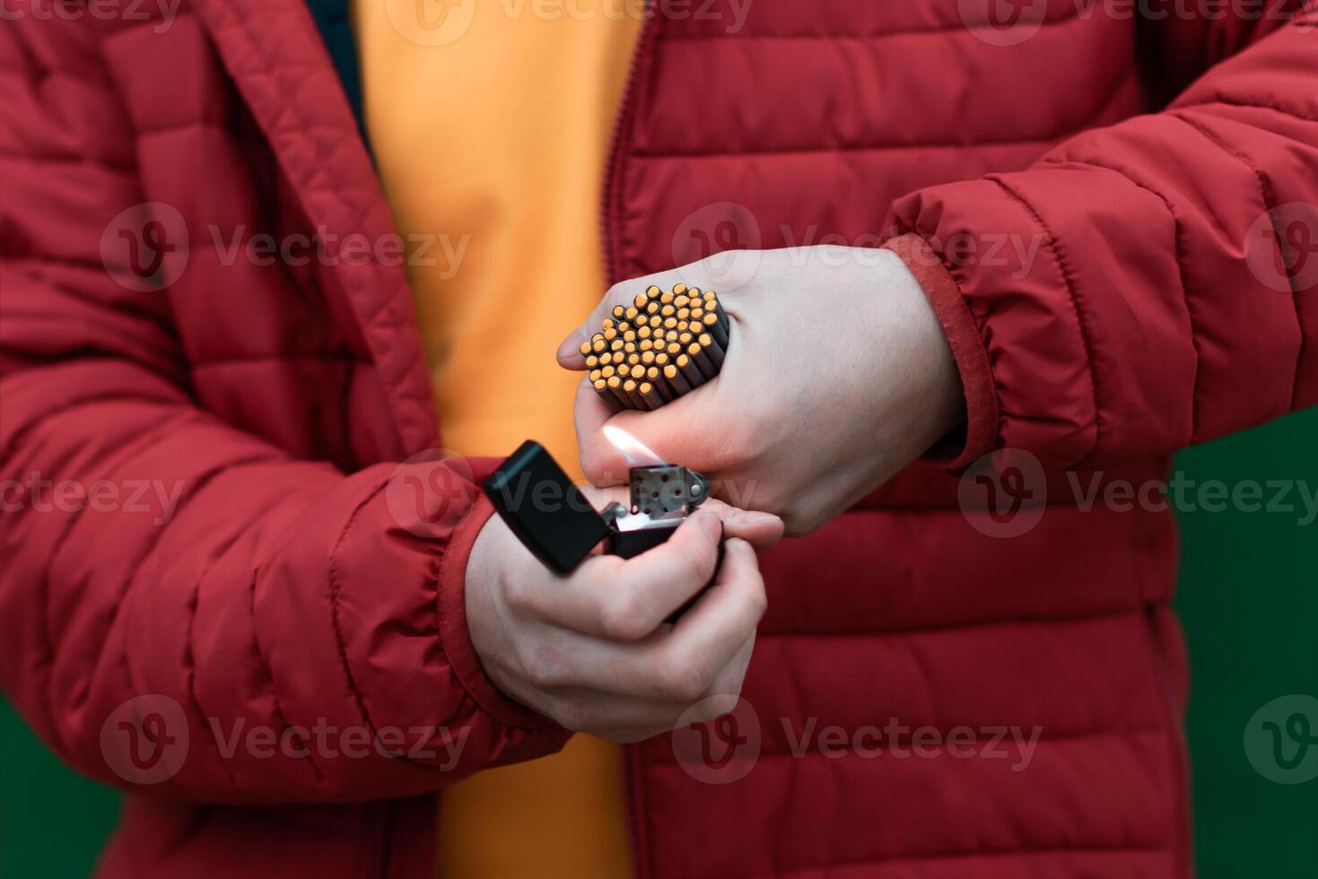 Man in Red Jacked Lighting Up Many Small Black Firecrackers in his Hand Using Gasoline Lighter. Guy Getting Ready for New Year Fun with Fireworks or Pyrotechnic Products photo