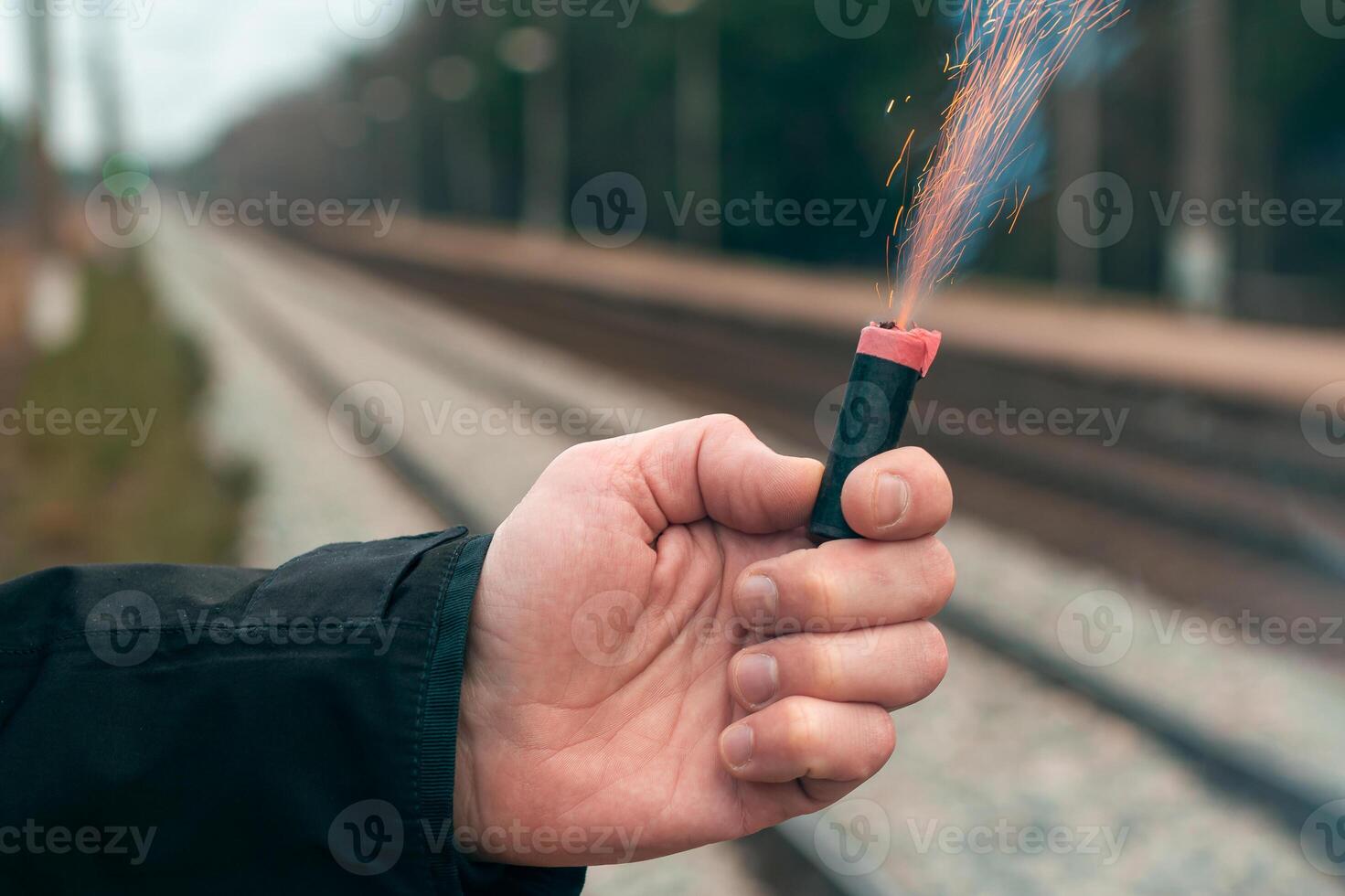 The Firecracker in a Hand. Man Holding a Burning Petard in His Hand. A Human with a Pyrotechnics that Burns with Sparks and Smoke Outdoors photo