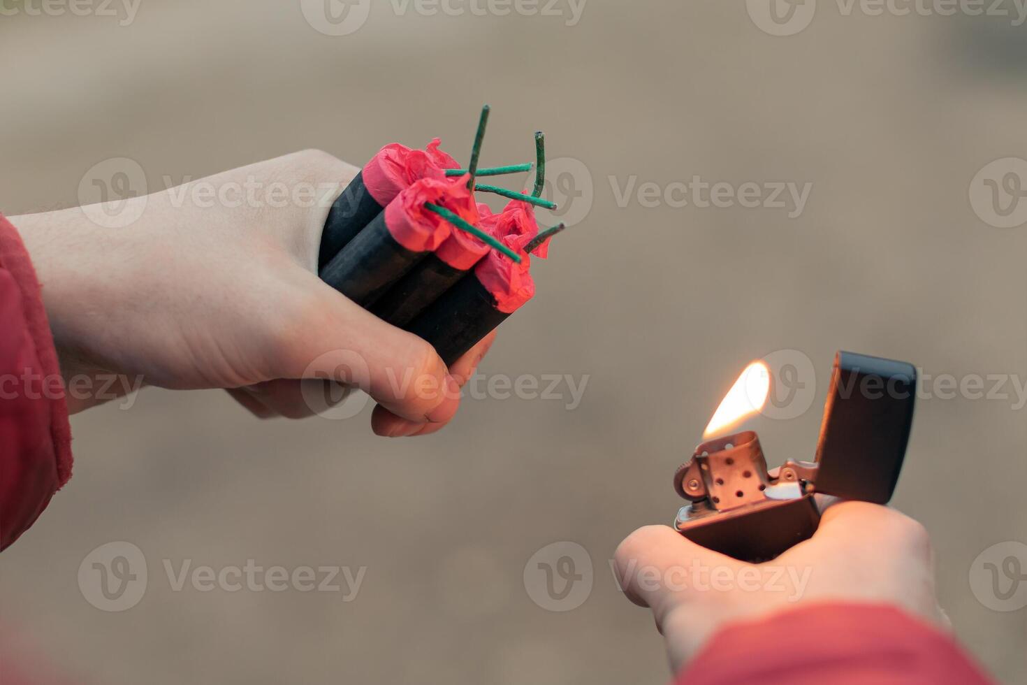 Man Lighting Up Several Firecrackers in his Hand Using Gasoline Lighter. Guy Getting Ready for New Year Fun with Fireworks or Pyrotechnic Products - CloseUp Shot, Rear View photo