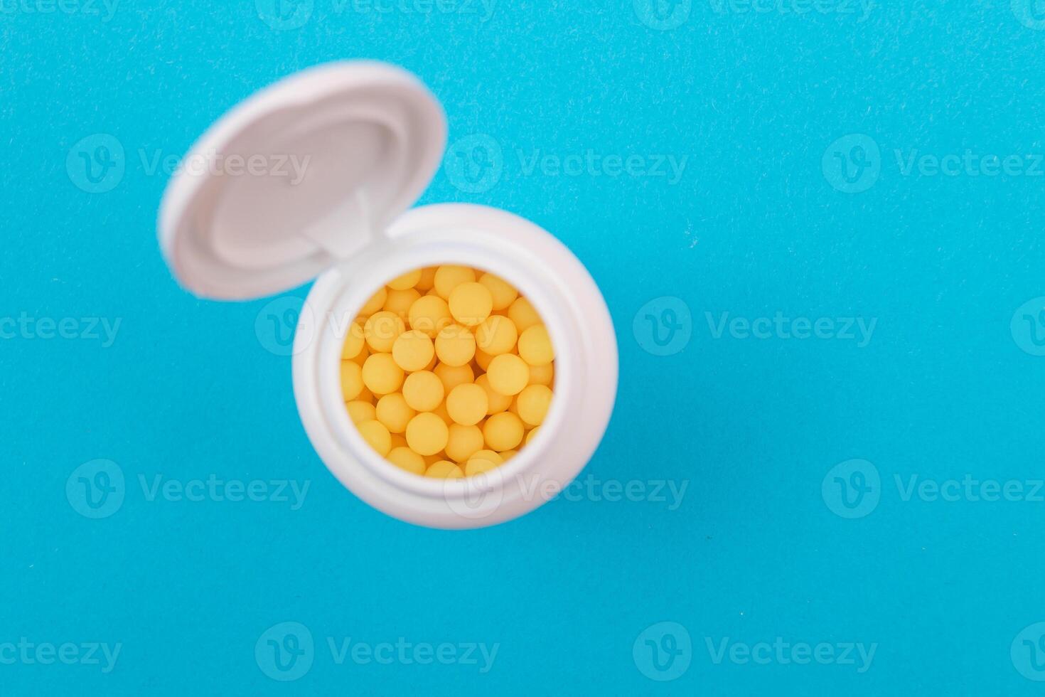 Global Pharmaceutical Industry and Medicinal Products - Yellow Vitamins or Pills in Bottle Lying on Blue Background. Copy Space, Top View, Flat Lay photo