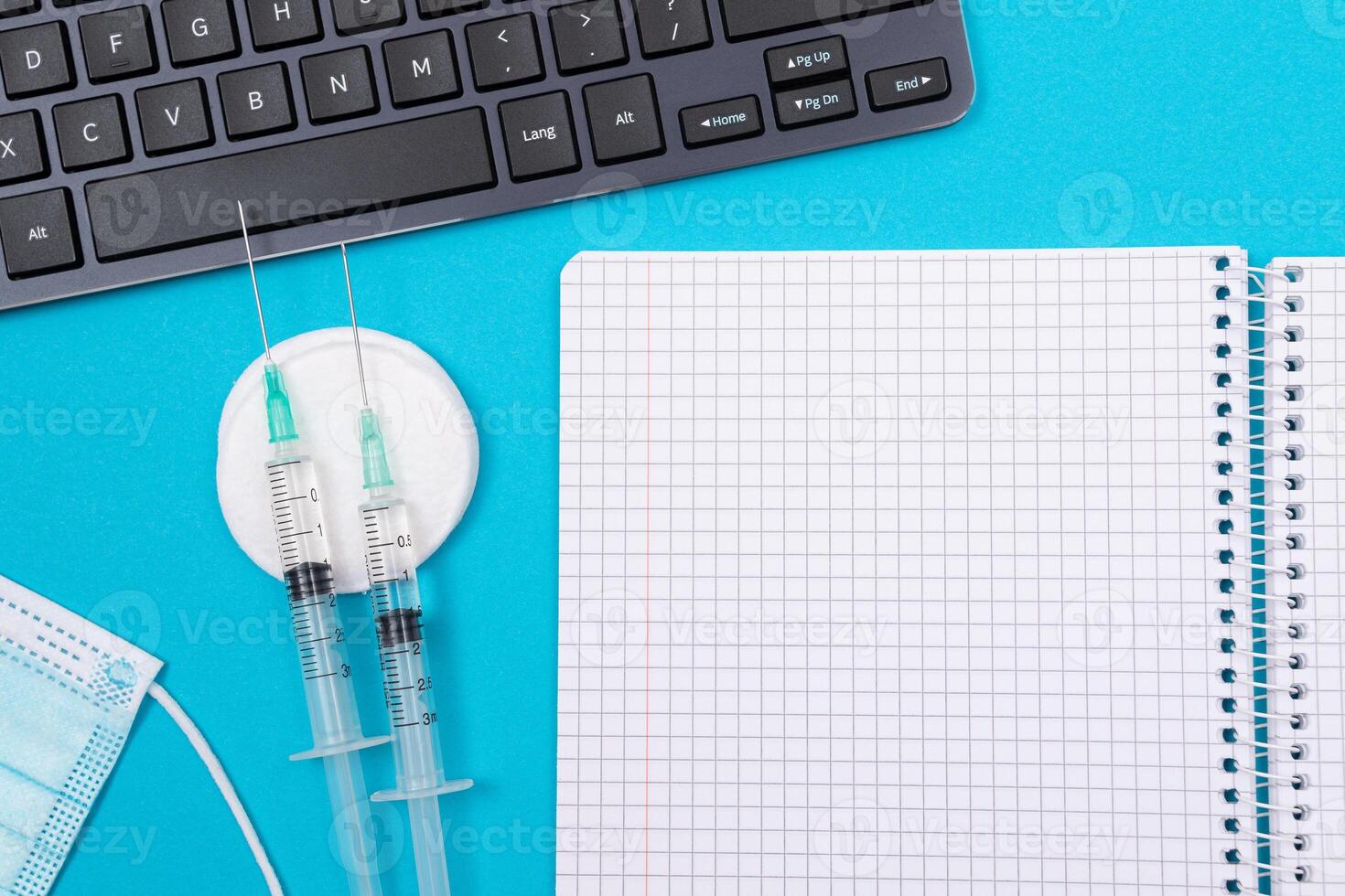 Vaccination, Immunology or Revaccination Concept - Two Medical Syringe Lying on Blue Table in Doctor's Office in a Hospital or Clinic. Opened Blank Notepad - Mock Up with Copy Space photo