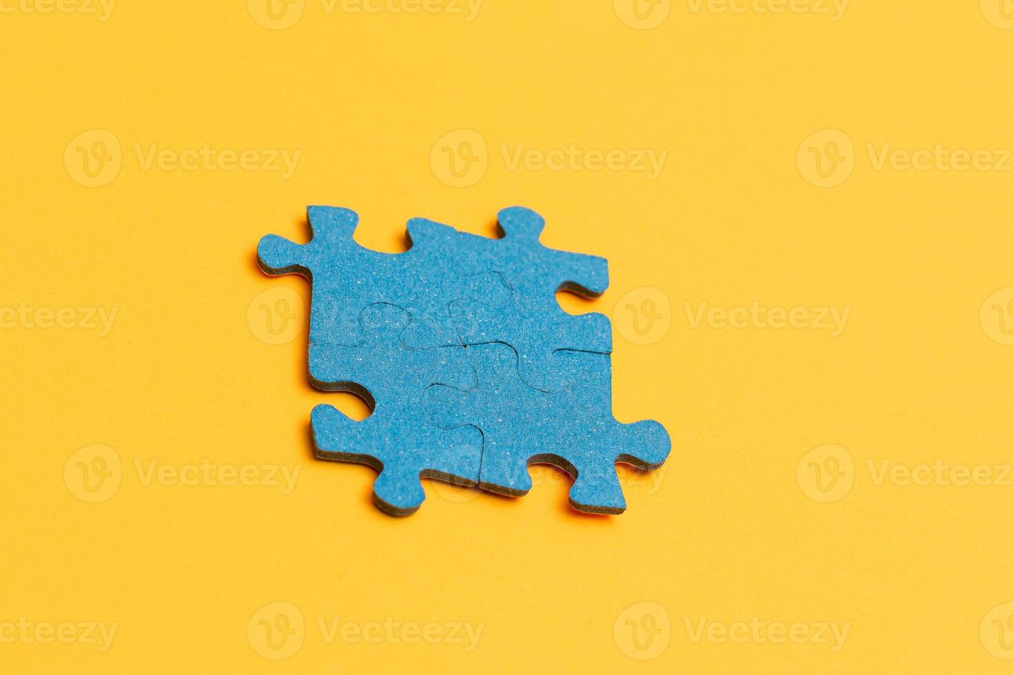 Top View of a Blue Puzzle Pieces Lie on the Yellow Background photo