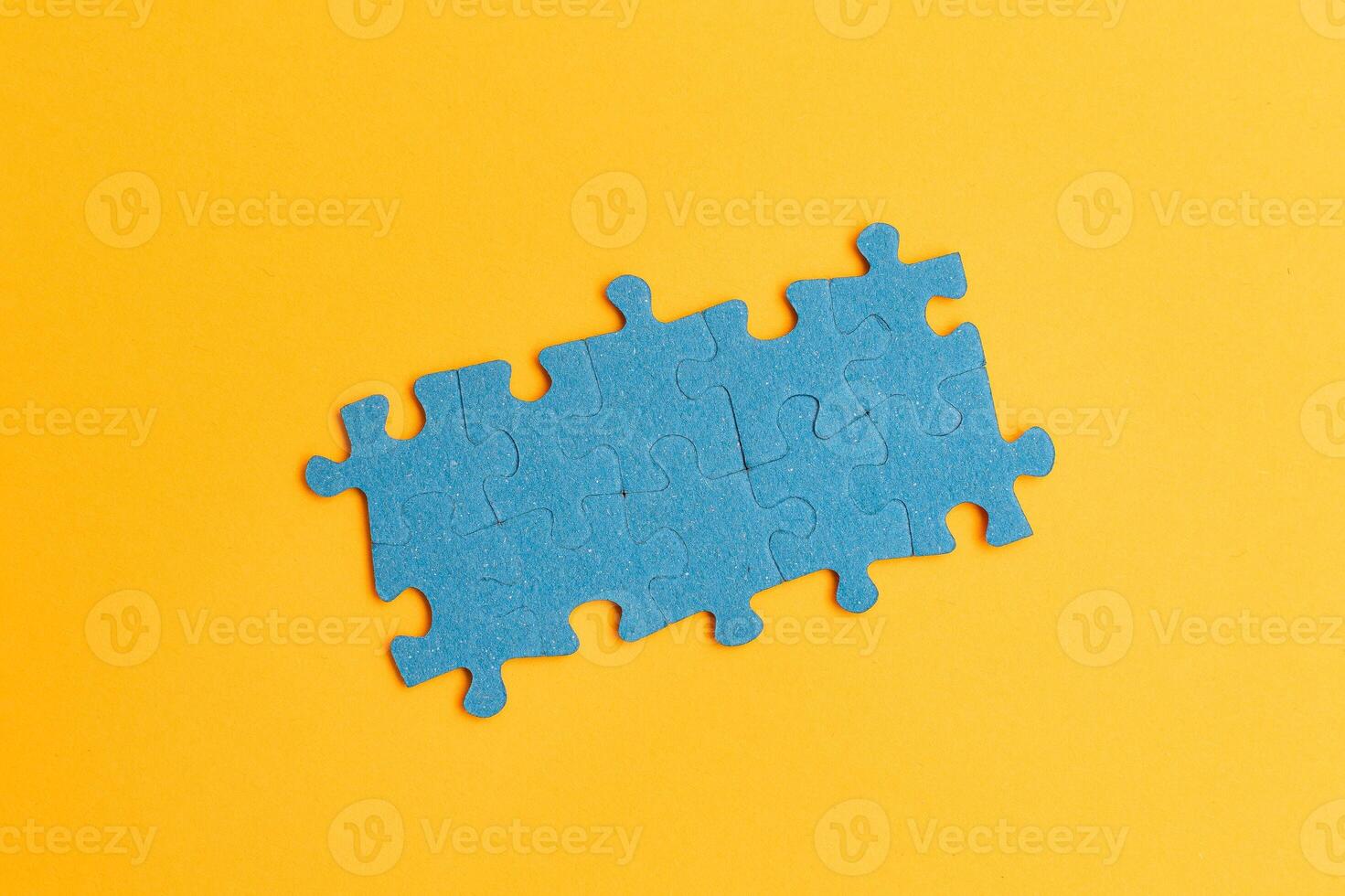 Top View of a Blue Puzzle Pieces Lie on the Yellow Background photo