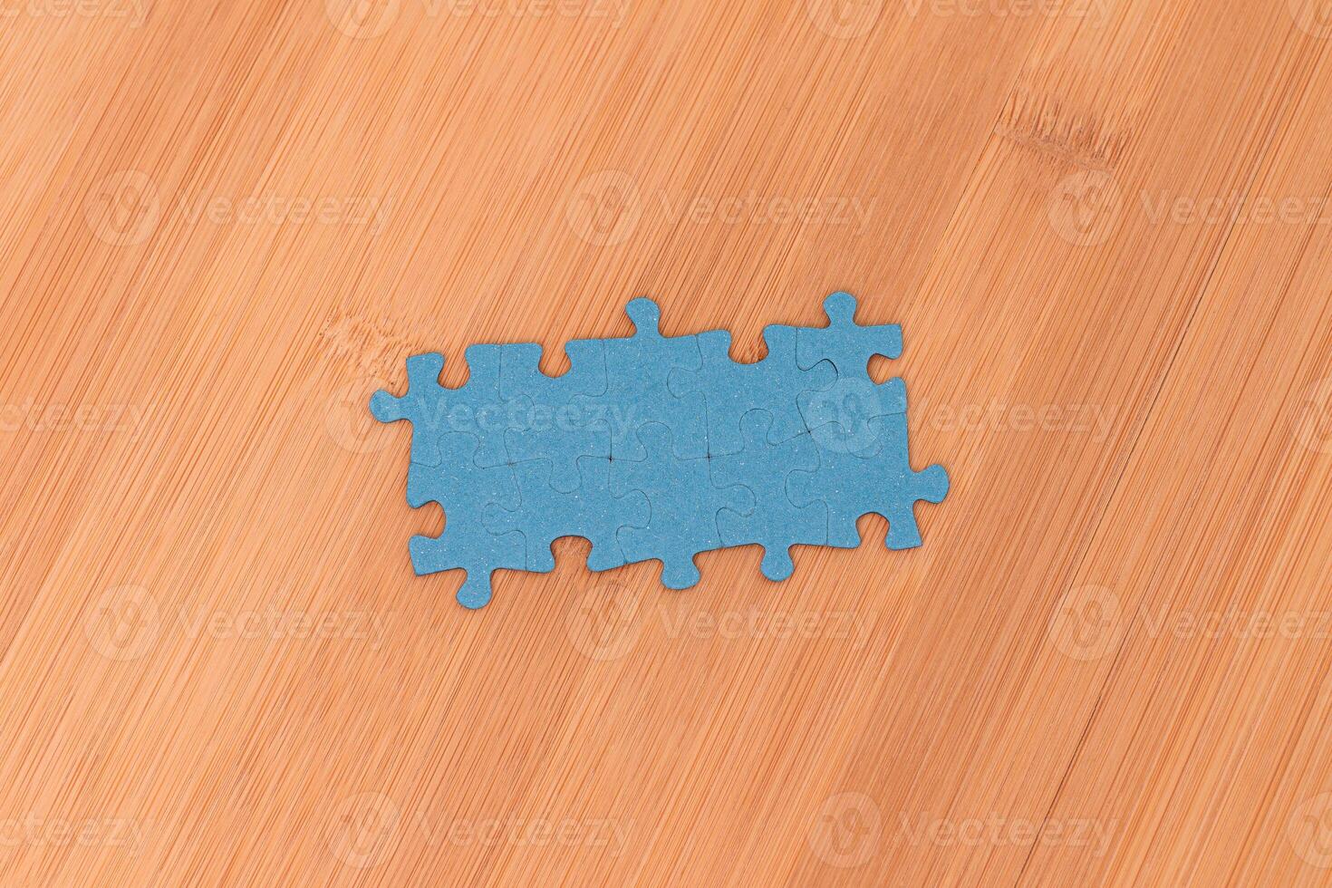 Top View of a Blue Puzzle Pieces Lie on the Wooden Table photo