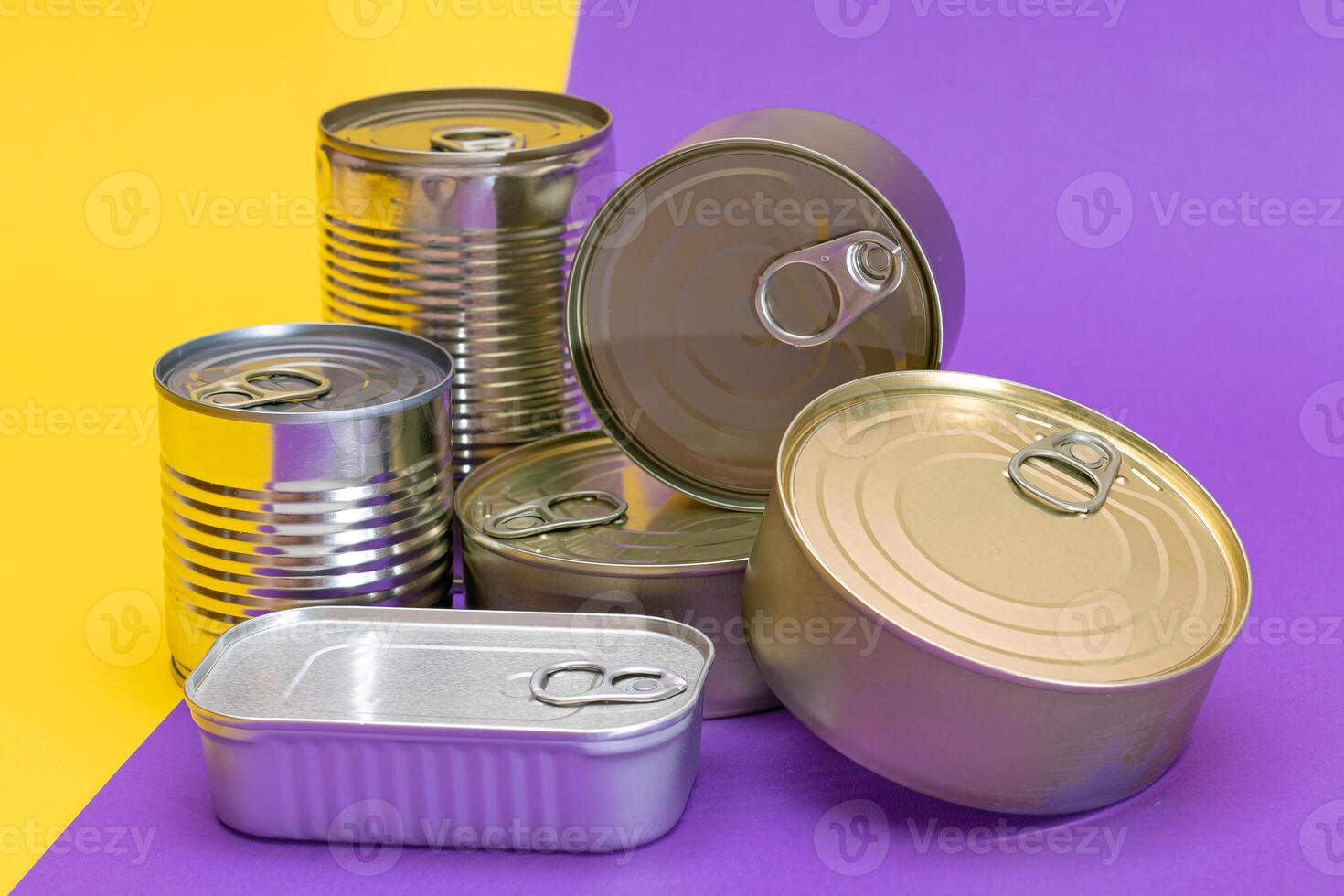 A Group of Stacked Tin Cans with Blank Edges on Split Yellow and Violet Background. Canned Food. Different Aluminum Cans for Safe and Long Term Storage of Food. Steel Sealed Food Storage Containers photo