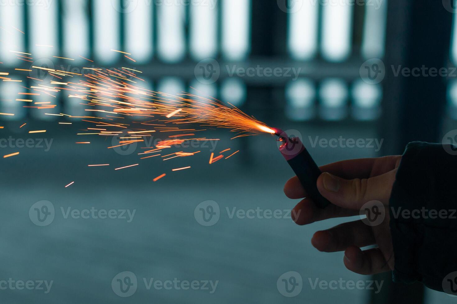 Burning Firecracker with Sparks. Guy Holding a Petard in a Hand. Loud and Dangerous New Year's Entertainment. Hooliganism with Pyrotechnics. Noise of Firecrackers in Public Places photo