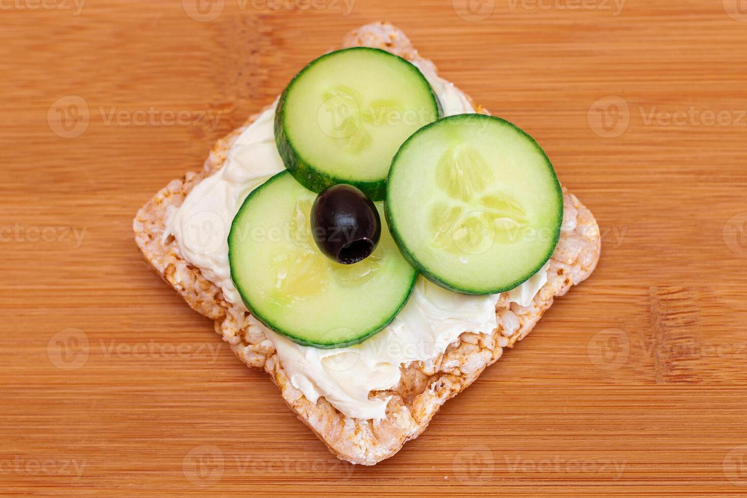 Rice Cake Sandwich with Fresh Cucumber, Cream Cheese and Olives on Bamboo Cutting Board. Easy Breakfast. Diet Food. Quick and Healthy Sandwiches. Crispbread with Tasty Filling. Healthy Dietary Snack photo