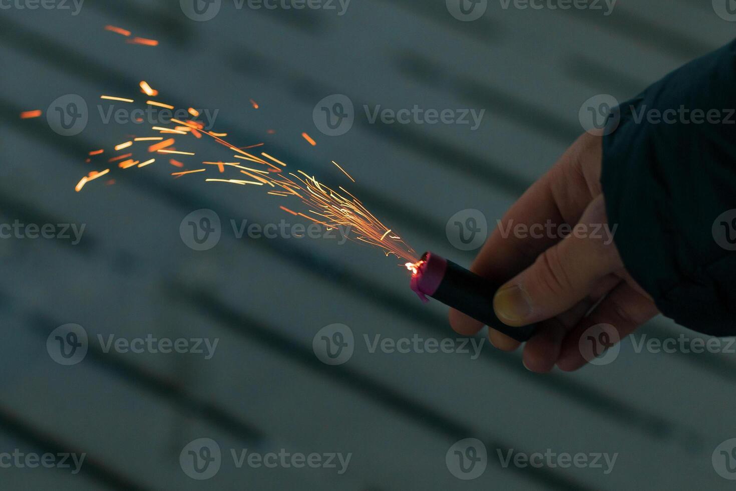 Burning Firecracker with Sparks. Guy Holding a Petard in a Hand. Loud and Dangerous New Year's Entertainment. Hooliganism with Pyrotechnics. Noise of Firecrackers in Public Places photo