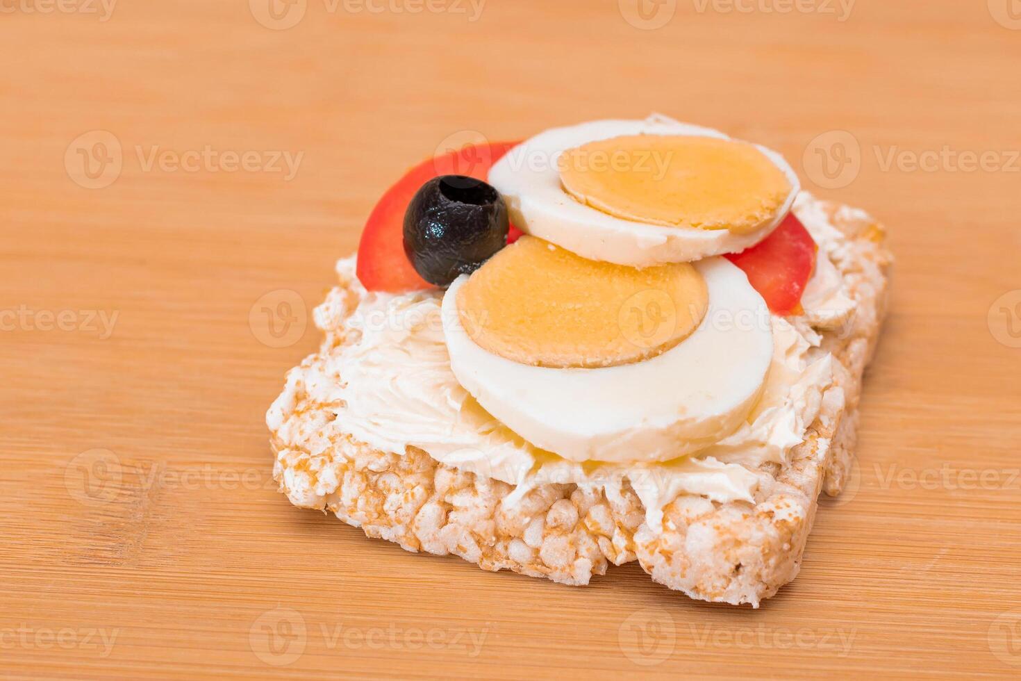 Rice Cake Sandwich with Tomato, Eggs and Olives on Bamboo Cutting Board. Easy Breakfast. Diet Food. Quick and Healthy Sandwiches. Crispbread with Tasty Filling. Healthy Dietary Snack photo