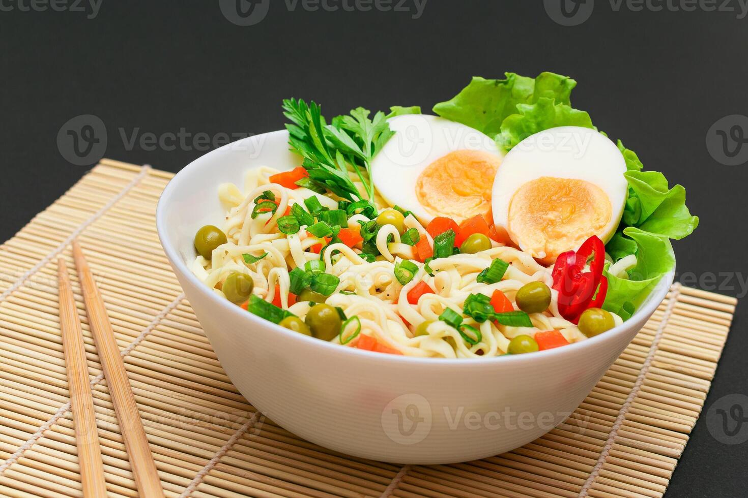 Beautiful Noodle Dish with Green Pea, Carrot, Eggs, Red Hot Pepper and Greens on Sushi Mat. Instant Noodles with Vegetables photo