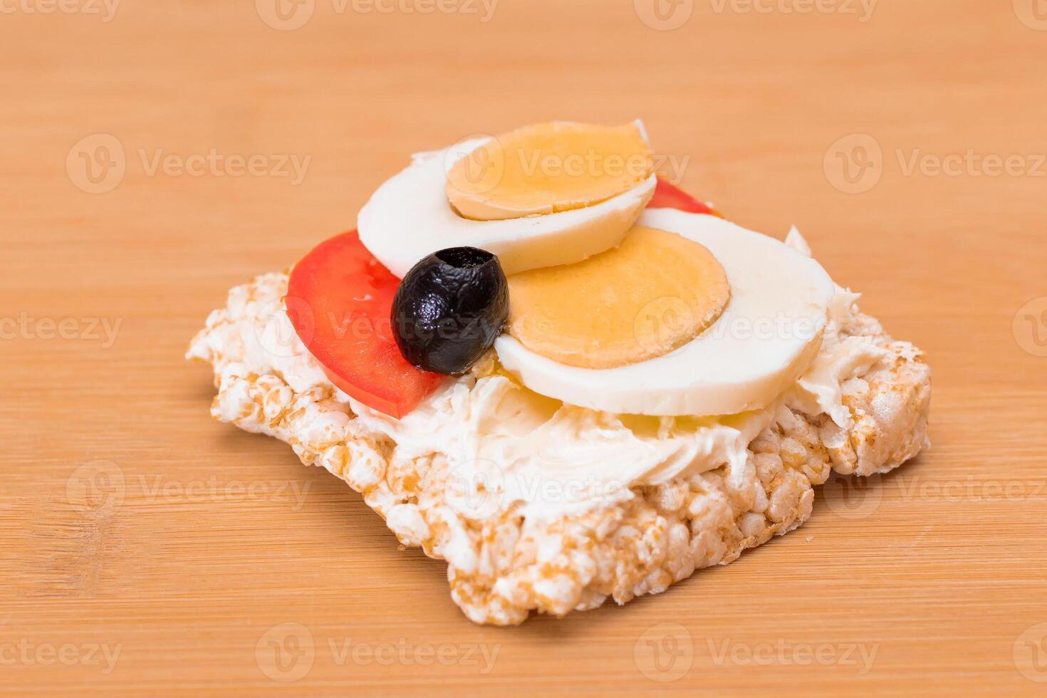 Rice Cake Sandwich with Tomato, Eggs and Olives on Bamboo Cutting Board. Easy Breakfast. Diet Food. Quick and Healthy Sandwiches. Crispbread with Tasty Filling. Healthy Dietary Snack photo
