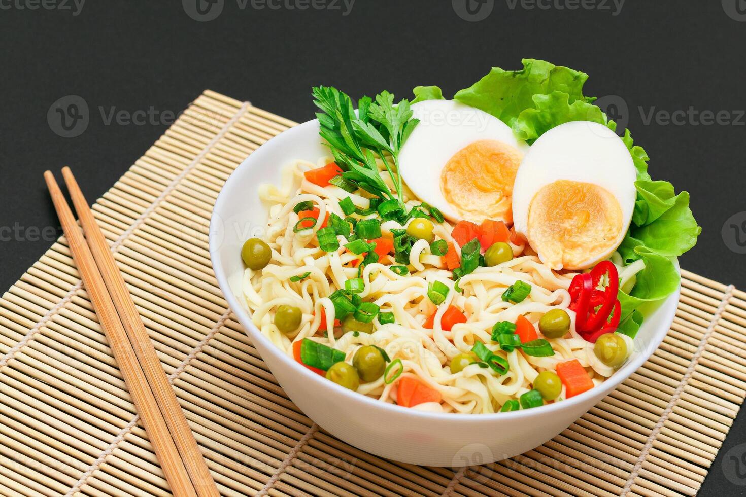 Beautiful Noodle Dish with Green Pea, Carrot, Eggs, Red Hot Pepper and Greens on Sushi Mat. Instant Noodles with Vegetables photo