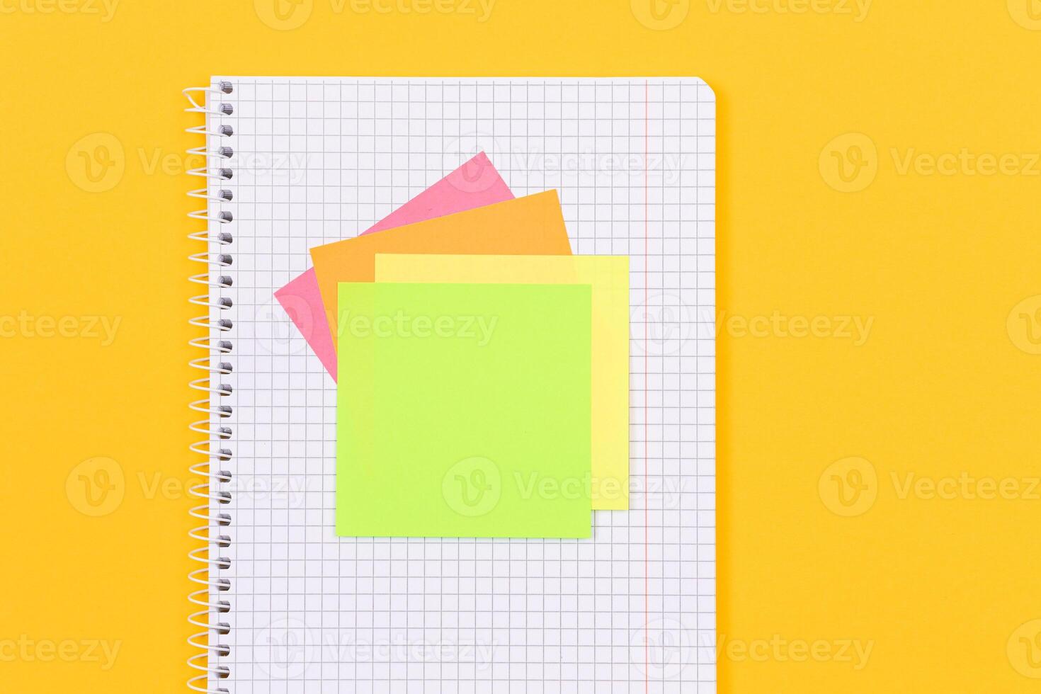 A Notepad with Sticky Notes Lying on Yellow Table - Blank Template. Top View, Flat Lay photo
