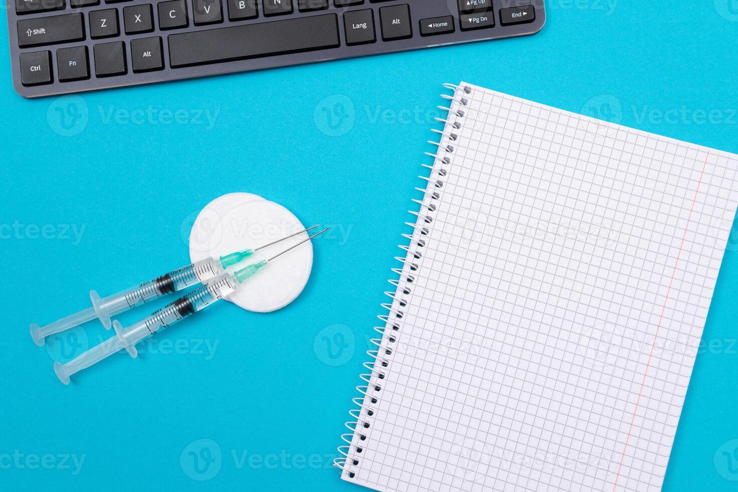 Vaccination, Immunology or Revaccination Concept - Two Medical Syringe Lying on Blue Table in Doctor's Office in a Hospital or Clinic. Opened Blank Notepad - Mock Up with Copy Space photo