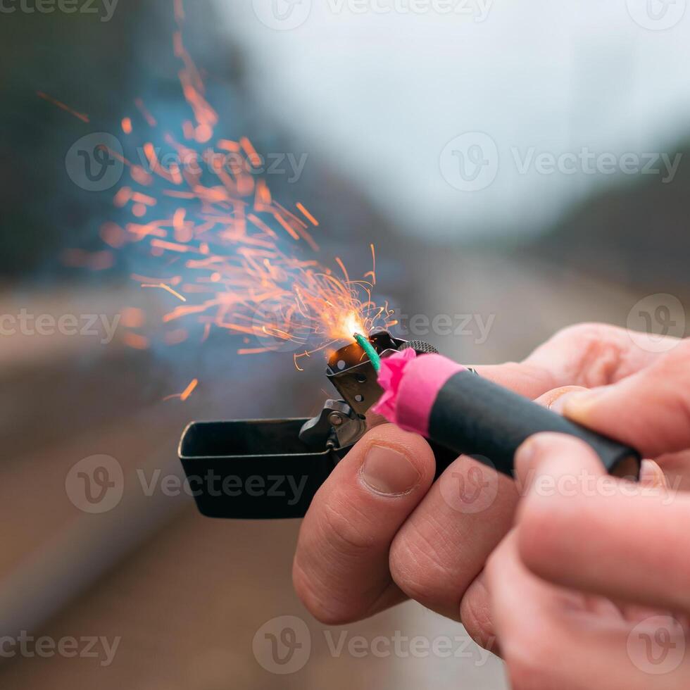 The Firecracker in a Hand. Man Holding a Burning Petard in His Hand. A Human with a Pyrotechnics that Burns with Sparks and Smoke Outdoors photo