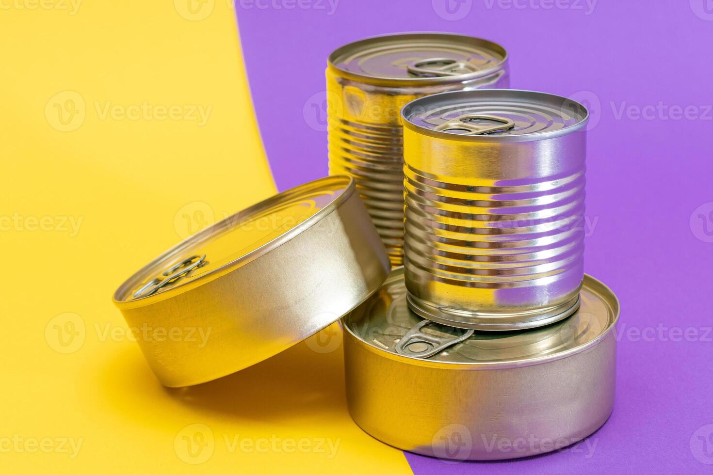 A Group of Stacked Tin Cans with Blank Edges on Split Yellow and Violet Background. Canned Food. Different Aluminum Cans for Safe and Long Term Storage of Food. Steel Sealed Food Storage Containers photo
