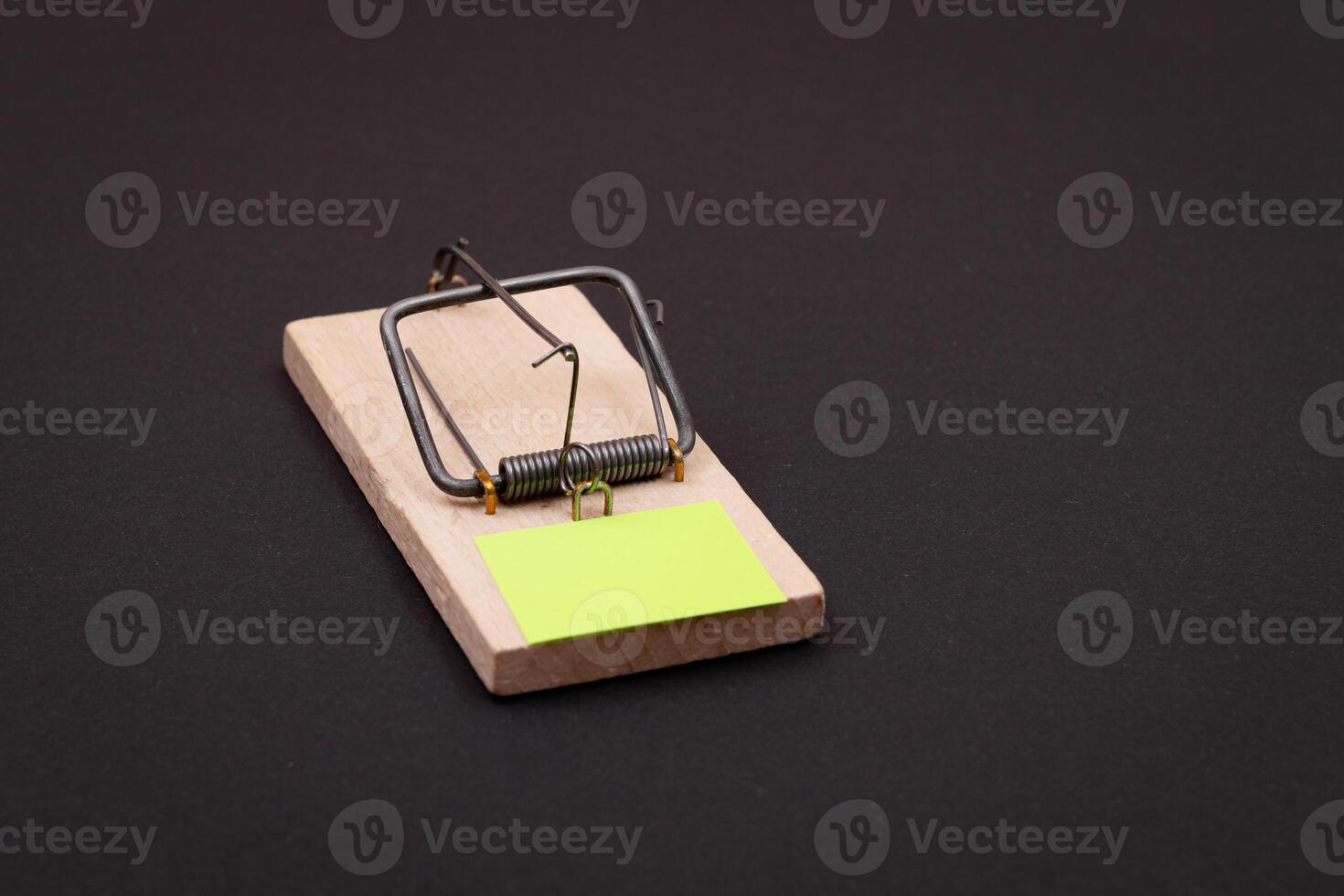 Blank Yellow Sheet of Paper in Wooden Mousetrap - Template. Small Memo Paper in Mouse Trap on Black Background photo
