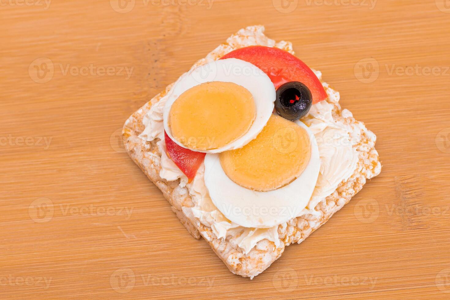Rice Cake Sandwich with Tomato, Eggs and Olives on Bamboo Cutting Board. Easy Breakfast. Diet Food. Quick and Healthy Sandwiches. Crispbread with Tasty Filling. Healthy Dietary Snack photo