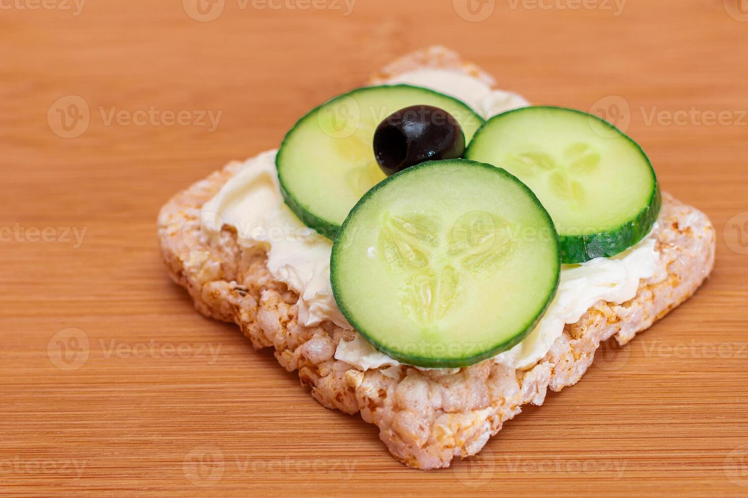 Rice Cake Sandwich with Fresh Cucumber, Cream Cheese and Olives on Bamboo Cutting Board. Easy Breakfast. Diet Food. Quick and Healthy Sandwiches. Crispbread with Tasty Filling. Healthy Dietary Snack photo