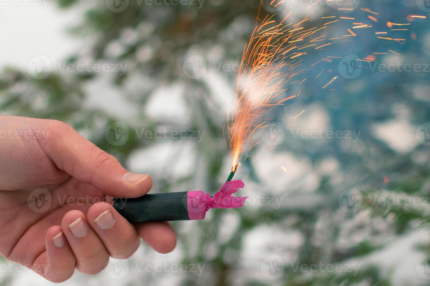 Burning Firecracker in a Hand. Guy Holding a Petard Outdoors in Winter at Daytime. Loud and Dangerous New Year's Entertainment. Hooliganism with Pyrotechnics. Noise of Firecrackers in Public Places photo