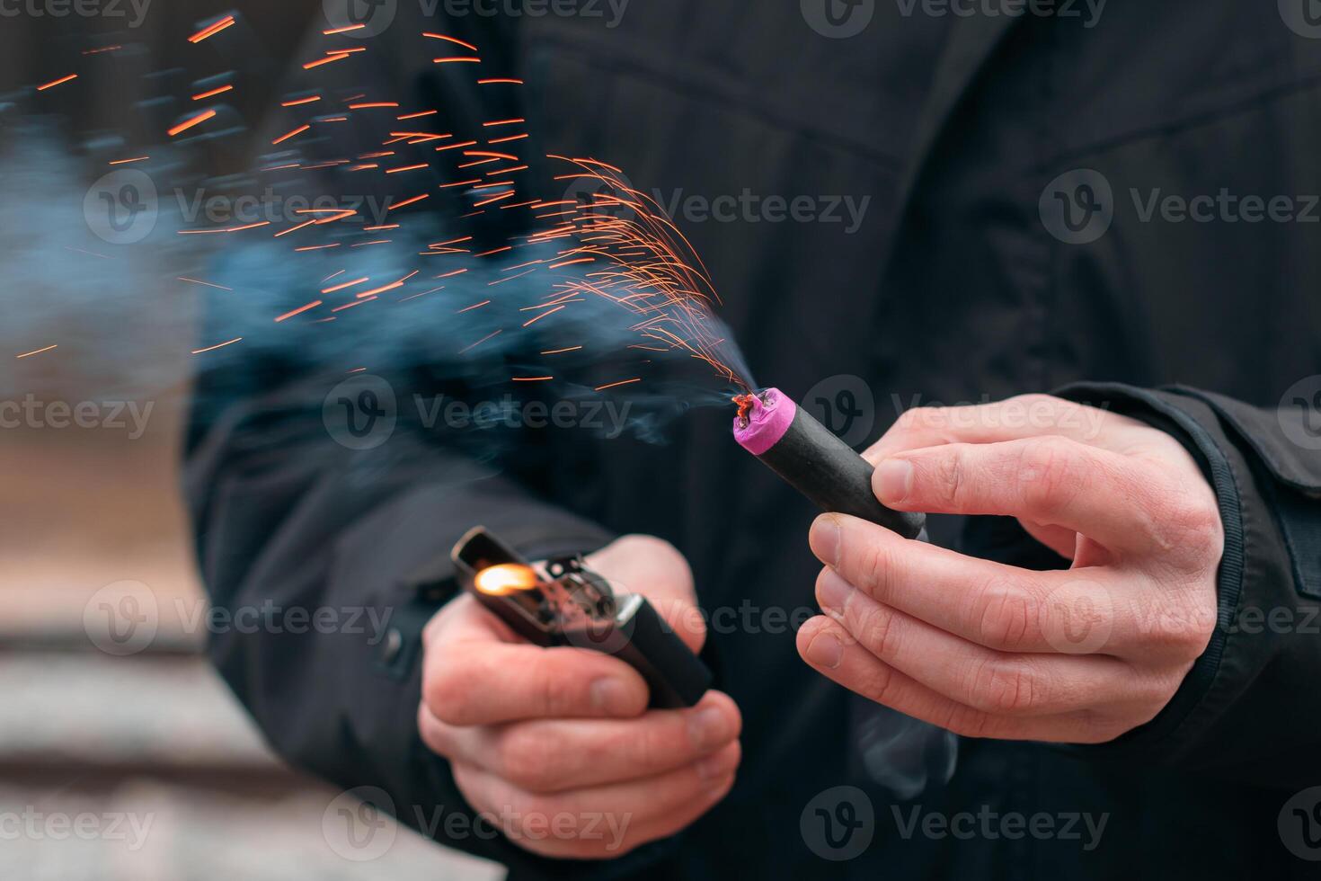 The Firecracker in a Hand. Man Holding a Burning Petard in His Hand. A Human with a Pyrotechnics that Burns with Sparks and Smoke Outdoors photo