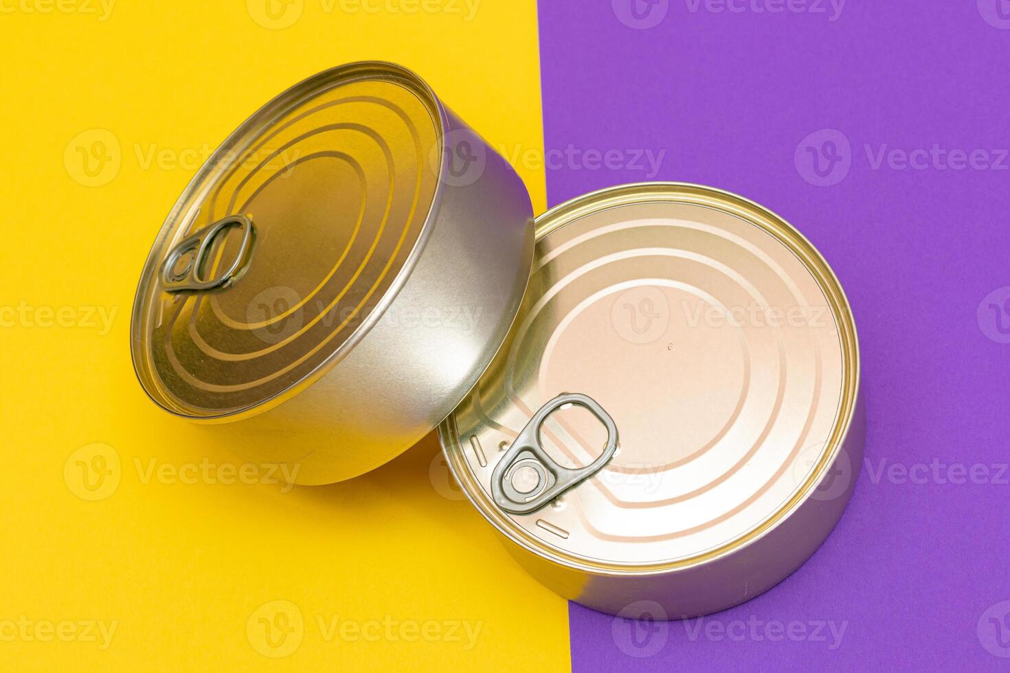 A Group of Stacked Tin Cans with Blank Edges on Split Yellow and Violet Background. Canned Food. Different Aluminum Cans for Safe and Long Term Storage of Food. Steel Sealed Food Storage Containers photo