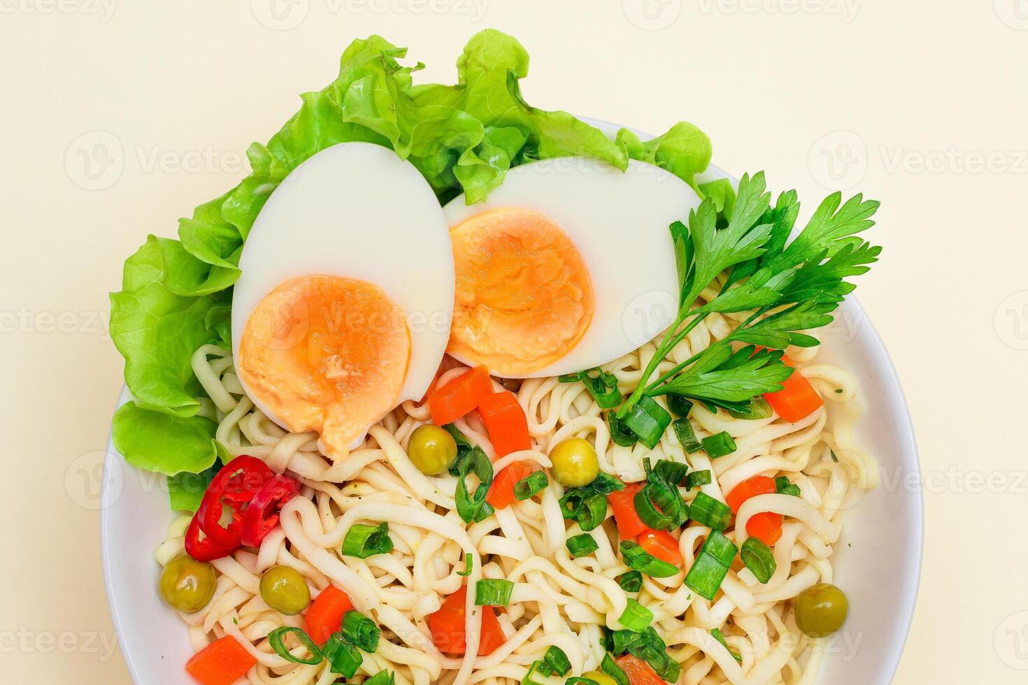 Beautiful Noodle Dish with Green Pea, Carrot, Eggs, Red Hot Pepper and Greens on White Background. Instant Noodles with Vegetables photo