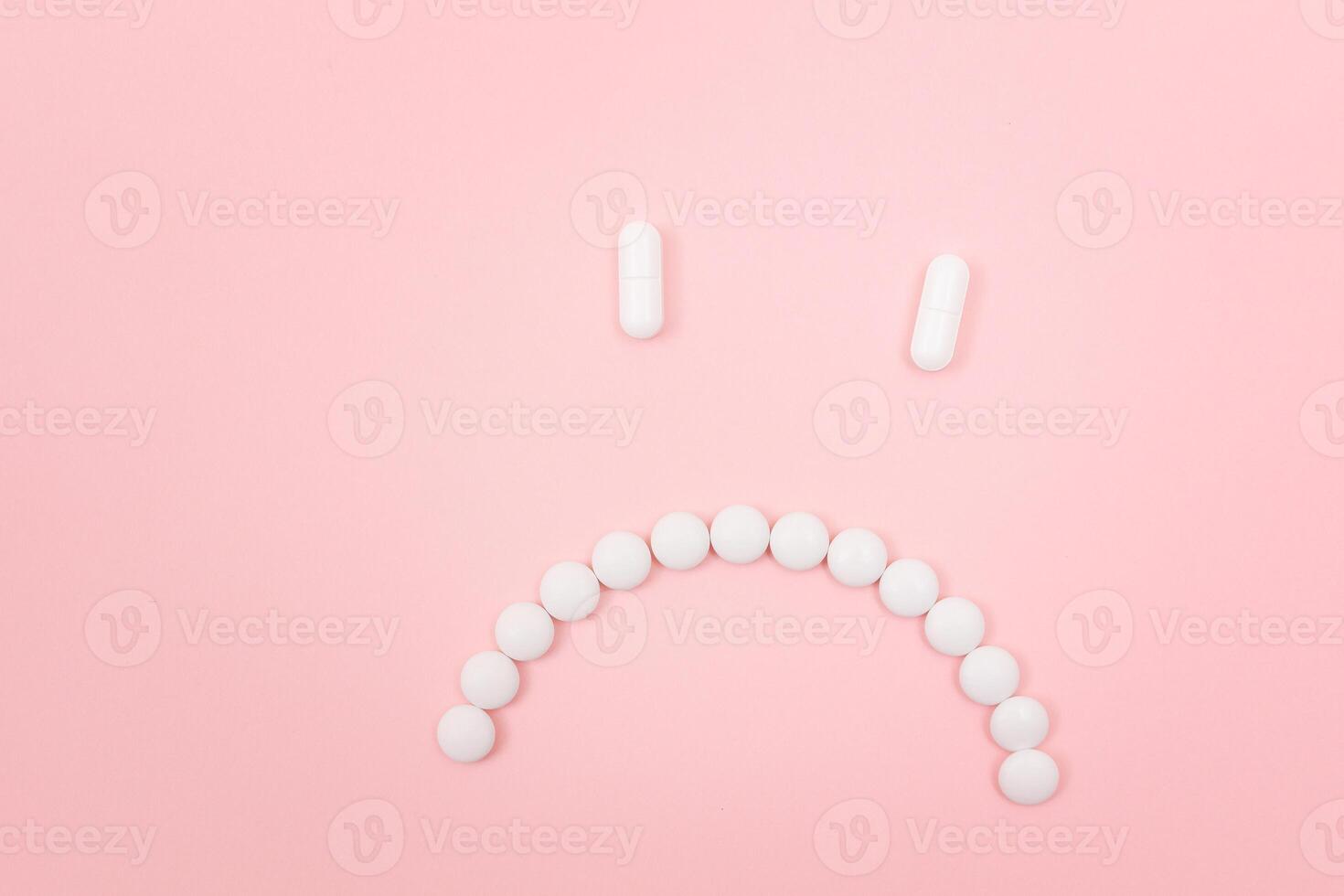 Pharma Harm. Sad Smiley Face Made from White Pills, Lying on Pink Backgrond. Global Pharmaceutical Industry and Medicinal Products photo