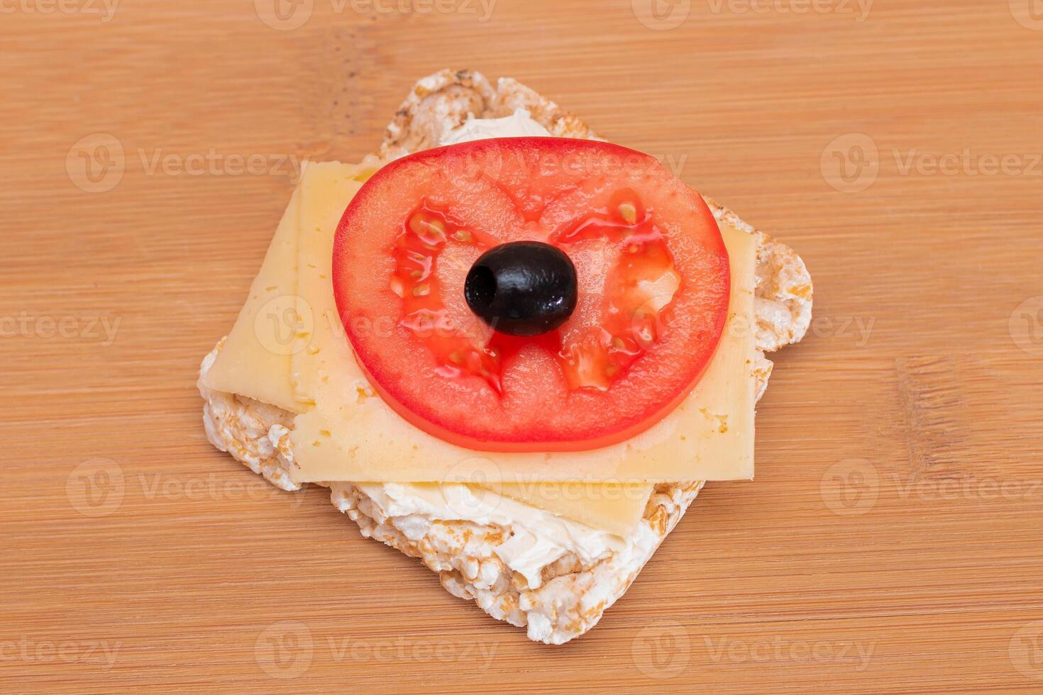 Rice Cake Sandwich with Tomato, Cheese and Olives on Bamboo Cutting Board. Easy Breakfast. Diet Food. Quick and Healthy Sandwiches. Crispbread with Tasty Filling. Healthy Dietary Snack photo