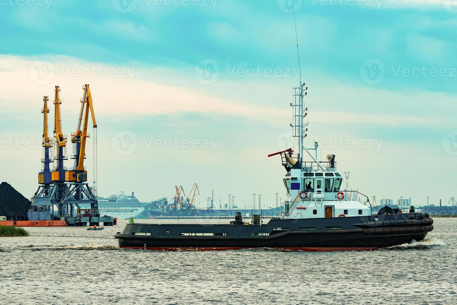 Black tug ship moving to the cargo terminal. Industrial service photo